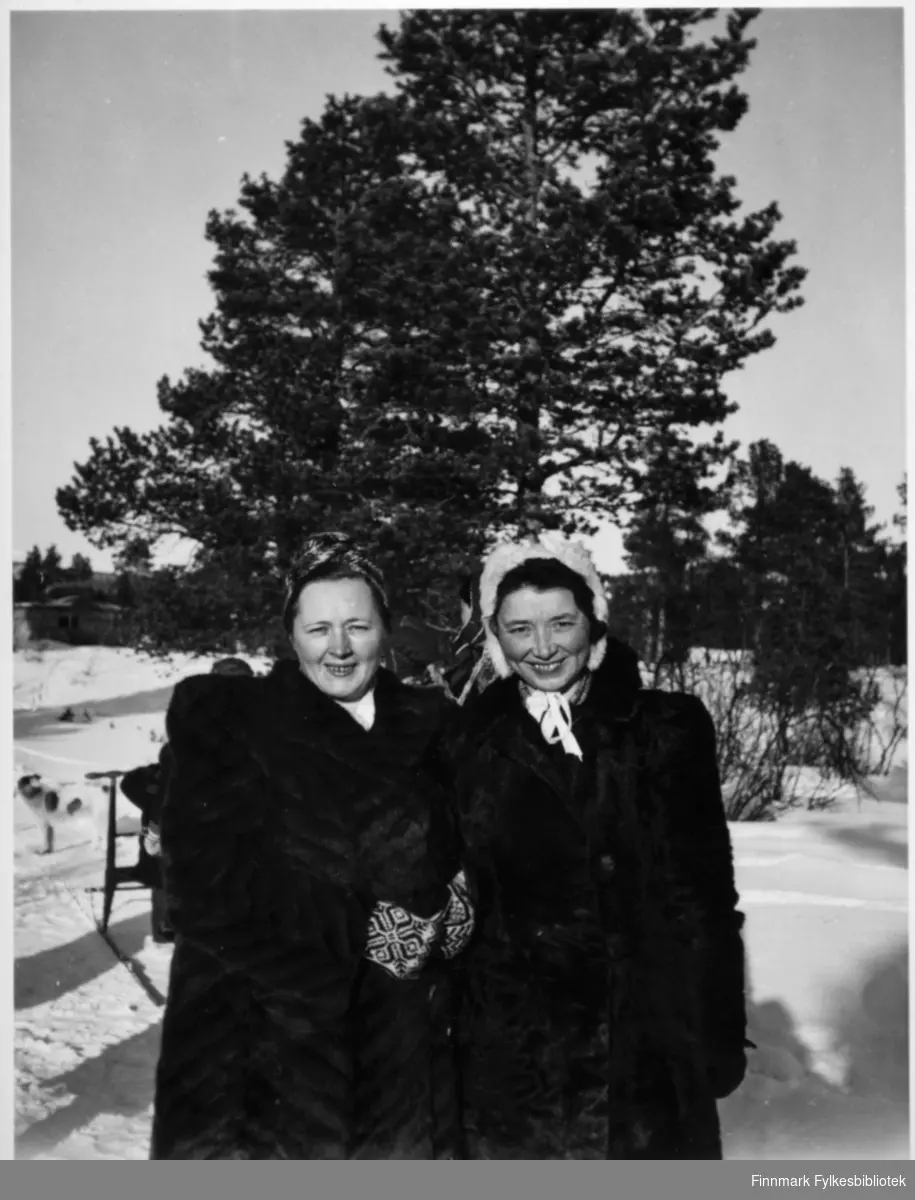 Sigdis Isaksen (til venstre), født Nilsen og Alfhild Berg (til høyre), født Næss. Stedet er muligens Karasjok. Sigdis Isaksen var kone til Einar Isaksen, de to drevet i Karasjok dagligvareforretning og landhandleri.
