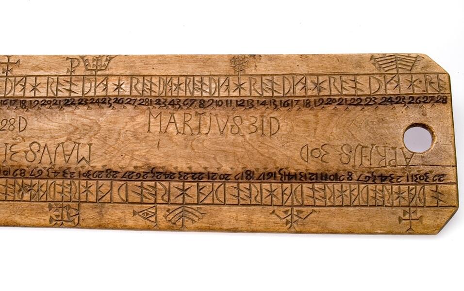 Platt bräde med runt hål vid ena ändan. Något modernare form. Månadernas namn är utsatta och vid varje runa står motsvarande datumsiffra.