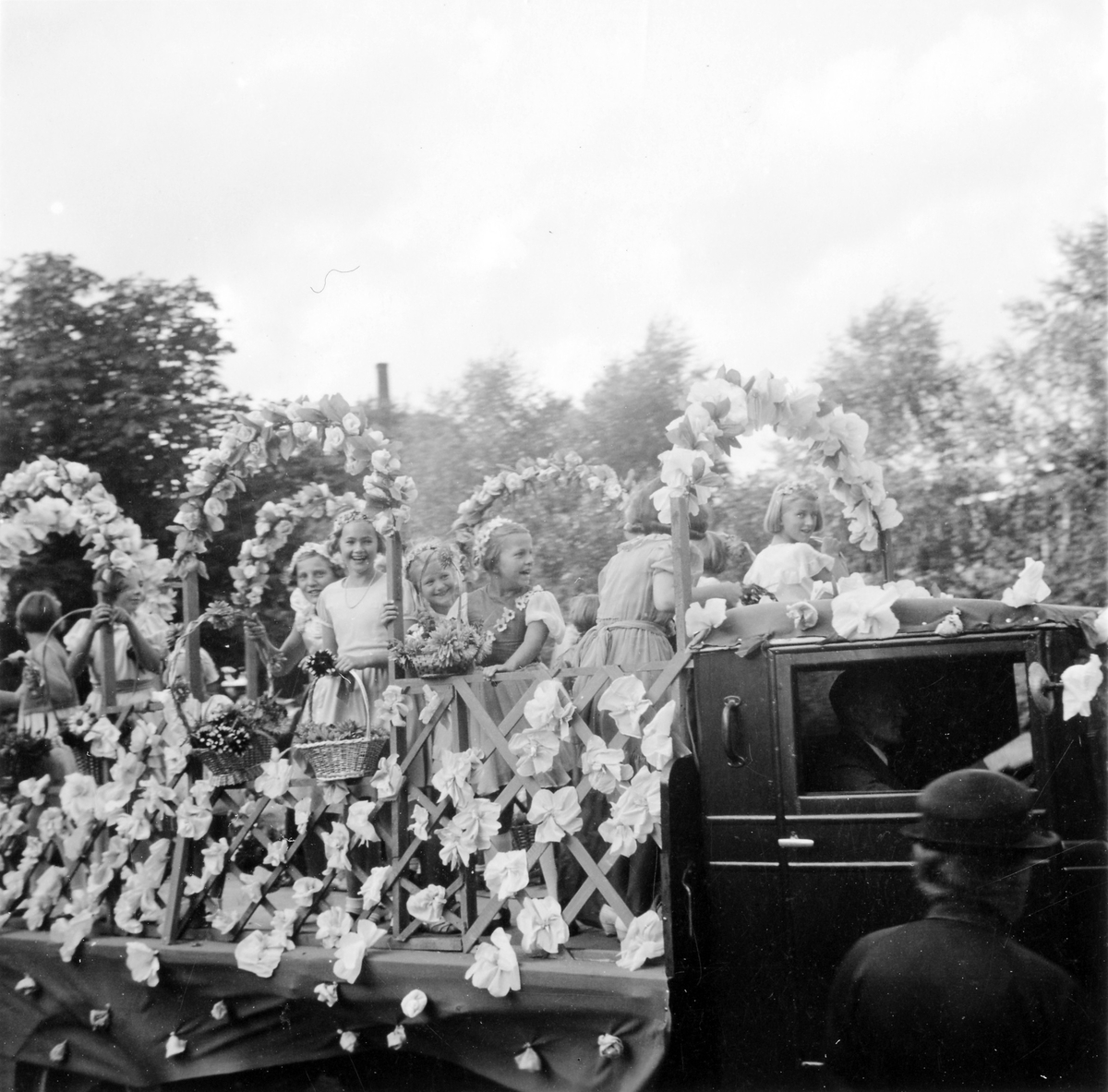 Barnens dag 1938. Flickor med blomsterkorgar sitter på ett flak på en flakbil i paraden.