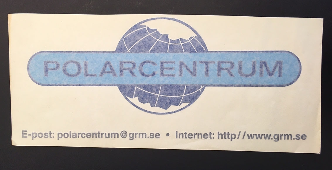 Dekal med texten"POLARCENTRUM" framför ett jordklot med Arktis och Antarktis markerat. Även epost-adress och webbadress.