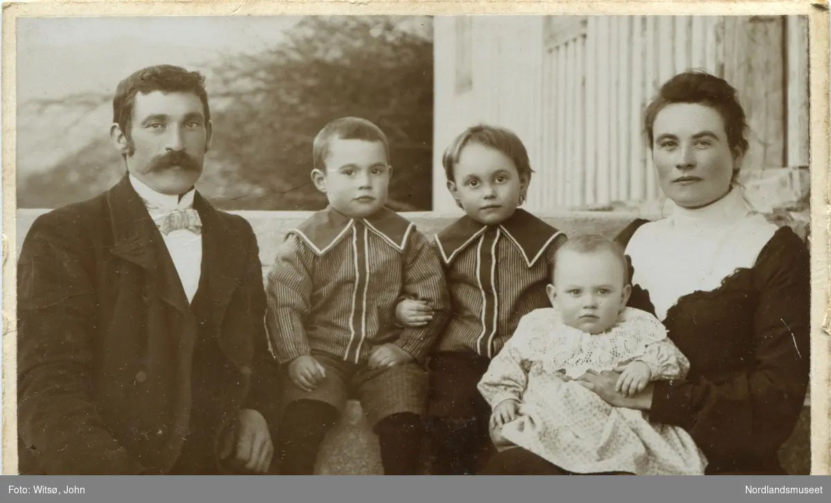 Familiebilde, ungt ektepar med tre barn, Simon og Kristine Lund med barna Karl, Ole og Einar. De sitter foran huset sitt på Lund.