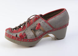 Grå sandalsko med røde detaljer og grov tresåle med hæl.