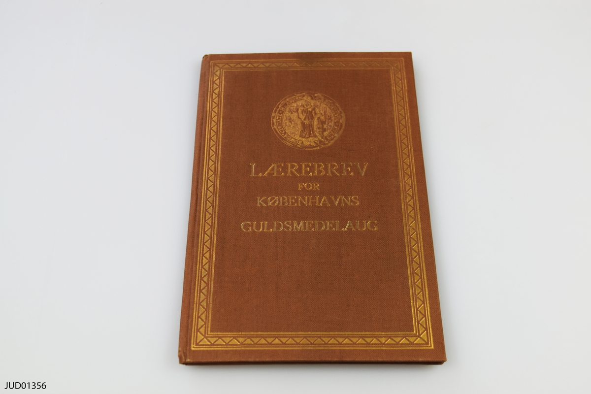 Gesällbrev i kassett. 
Laerebrev for Kobenhavns Guldsmedelaug utfärdat till Simon Feldbaum den 22 mars 1937 efter avslutad lärotid som silversmed hos Firmaet Grann & Laglye.