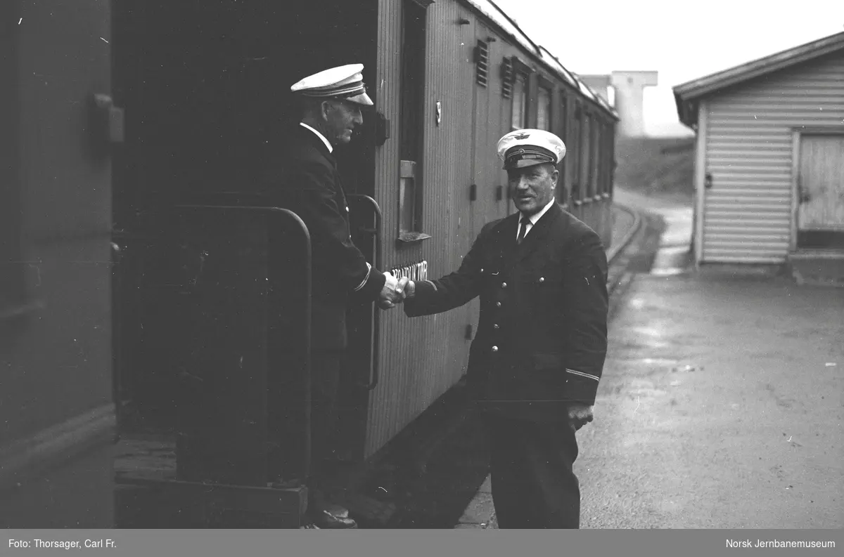 Siste tog på Sulitjelmabanen før banens nedleggelse har ankommet Finneid stasjon. Overkonduktør Einar Setså og stasjonsbetjent Kåre Olsen takker for samarbeidet