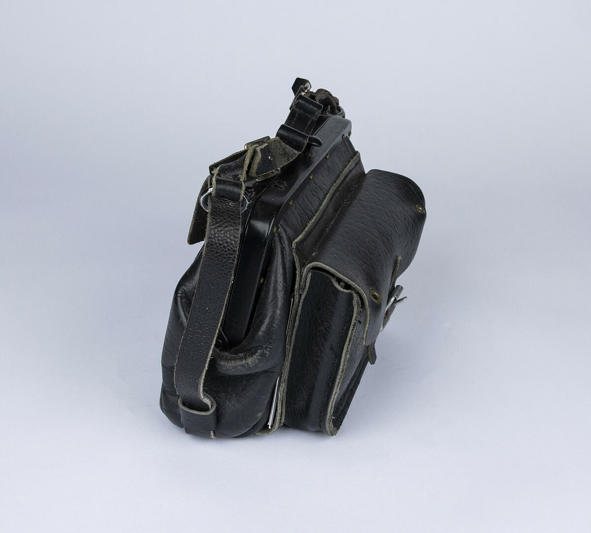 Konduktørveske i sort skinn med metallbøyle. Vesken har ulike rom for myntsorter, sedler, kort og andre ting. Vesken har to hull på fremste lomme der myntapparat kan plasseres.