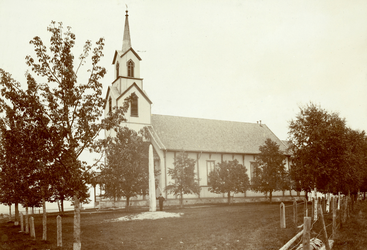 Bø kyrkje med bautaen reist i 1914 framfor