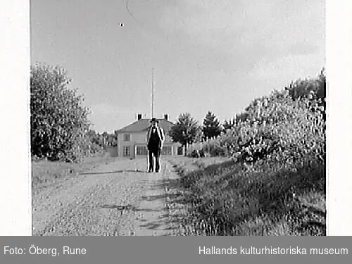 En man står på vägen som leder fram till Ölmevalla prästgård, troligen kyrkoherde Johannes Hof.
