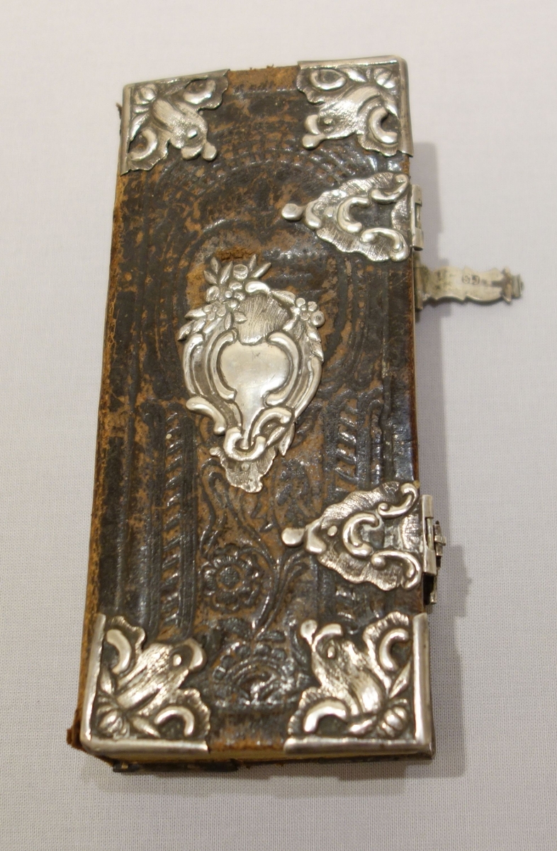 Skinninnbunnet salmebok med sølvbeslag. Preget dekor i skinnbinn