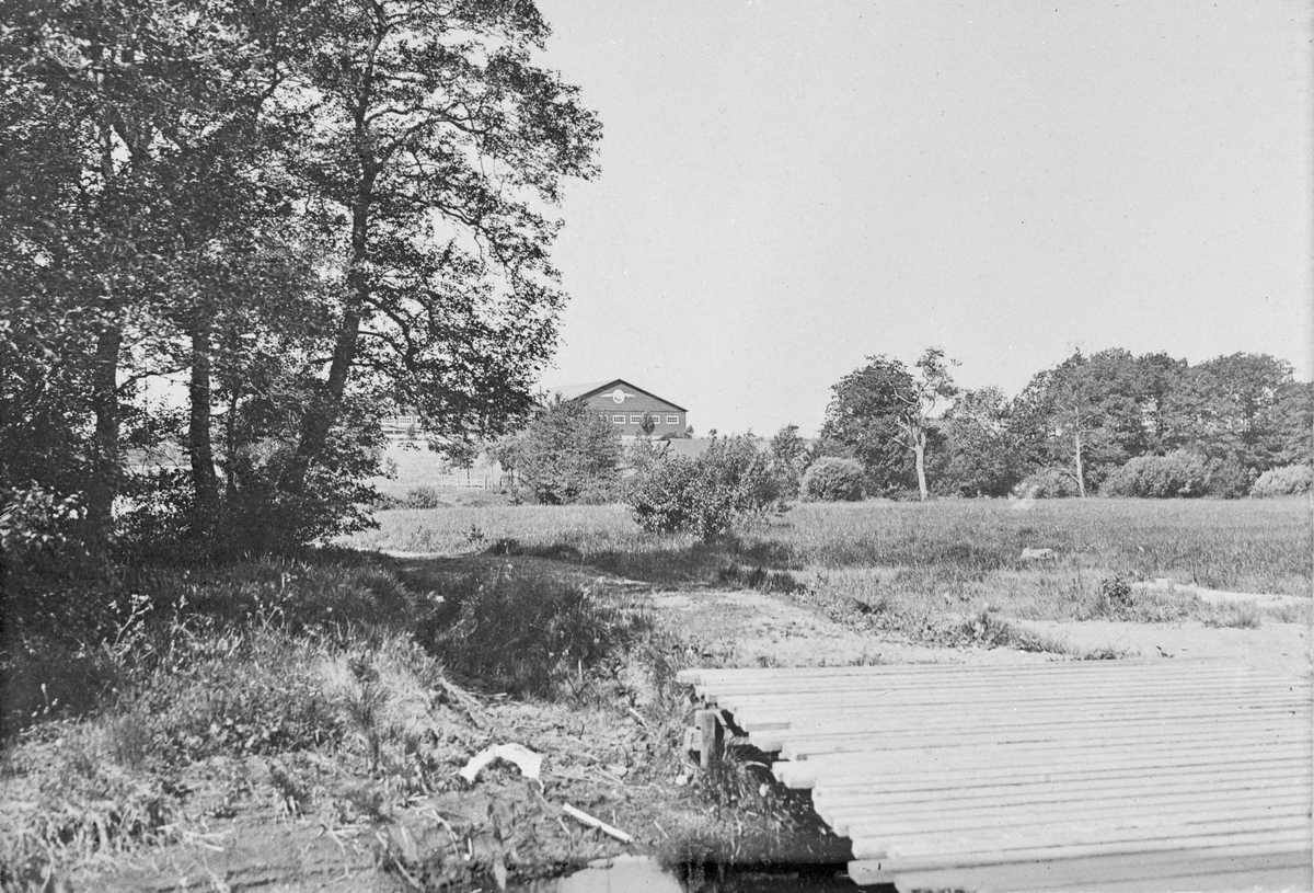 Exteriör av Thulinverken i Landskrona, slutet 1910-talet. Vy från håll, med bro i förgrunden.