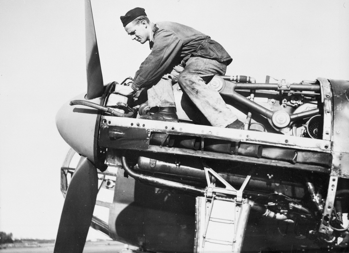 En flygtekniker arbetar med vänster motor på flygplan  B 18B, med motor Daimler Benz DB 605B. Omkring år 1950. Mekanikern sitter ovanpå motorn.