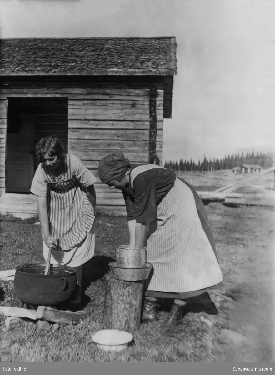 Två unga kvinnor utför sina sysslor vid en fäbod, troligen i Liden- eller Järkvissle-trakten. Ur en samling som tillhört Sellén, Järkvissle.