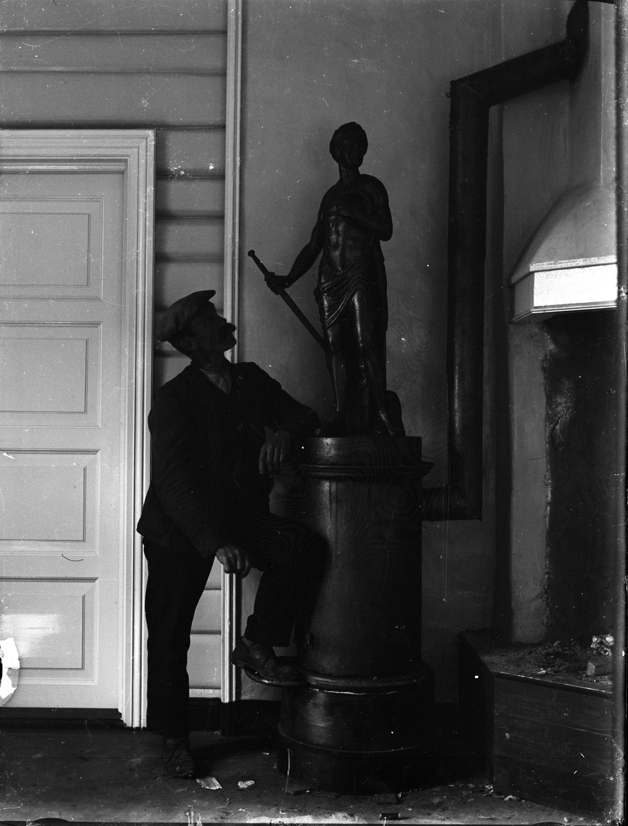 Fotosamling etter Kjetil Skomdal (1881-1971). Fotografen virket i perioden 1910 til 1960 og hadde eget mørkerom hvor han også tok imot film fra andre fotografer. I perioden var han også postbud i Fyresdal. Portrett av mann og statue.