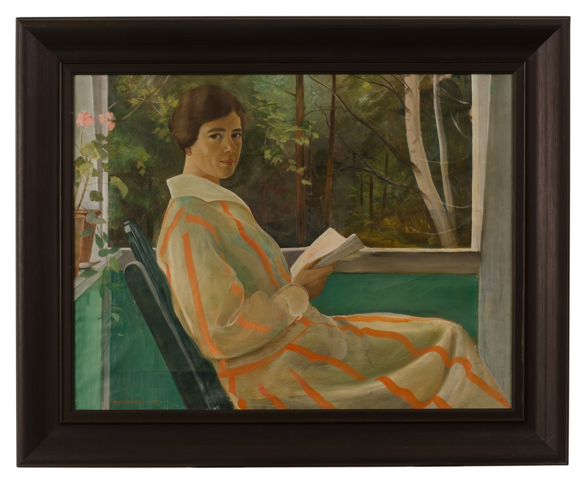 Gunhild Dahlgren sitter och läser på verandan i orangerandig klänning med pelargon bakom sig. I bakgrunden träd.