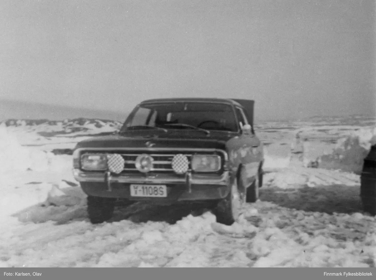 F.v. Bussesund-Sandfjord. Sen åpning av veien, bare sørpe. Man kan se en bil som står på veien: Y-11085 er en Opel Rekord C årsmodell 1967-69. (Produksjonen fortsatte t.o.m. 1971.) Stedet er Barvikmyra i Vardø i 1969.