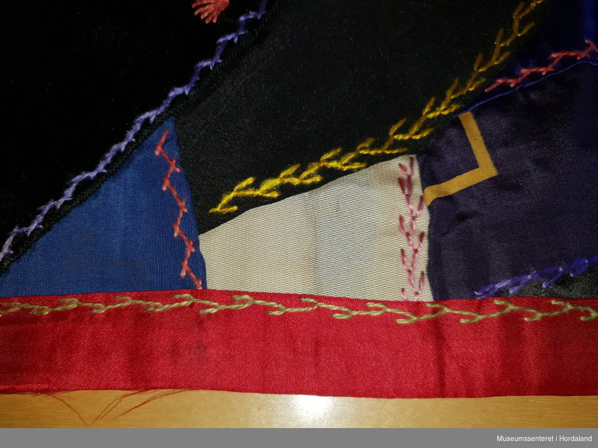 Teppet er en satt sammen av en mengde uregelmessige lapper, store og små, satt sammen i seks i hovedsaklig tilnærmet rektangler. Alle lappene varierer i størrelse, farge, form, stoff, kvalitet og mønster. Lappene er sydd sammen, og deretter dekorert og festet ekstra med ulike former for dekorativ kjedesøm u forskjellige farger. Hele teppet er kantet med rødt silkebånd, som også har kjedesting i overgang fra motiv til kant. 
Teppet er ikke foret, men et bakstykke i ett sammenhengende oransje bomullsstoff, med små, blomsterranker i lyseblå nyanser. 