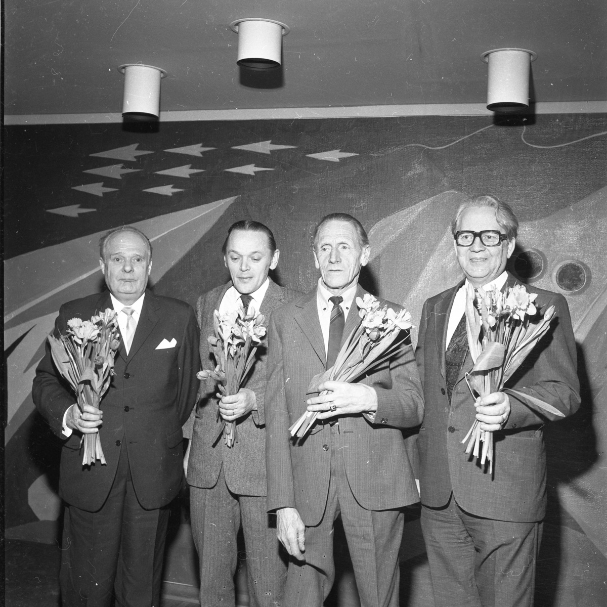 Fyra män med blommor i händerna.