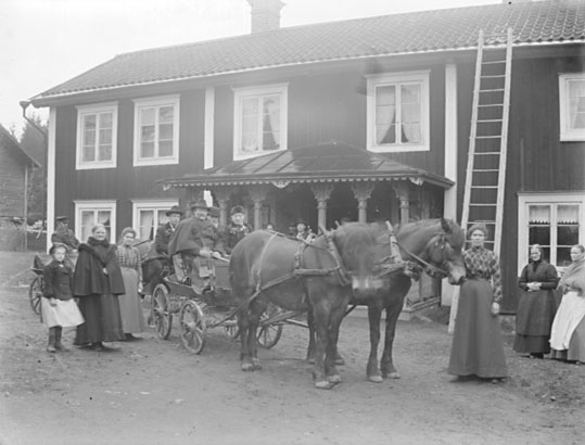 Grupporträtt, med hästar och vagn framför gårdens veranda.