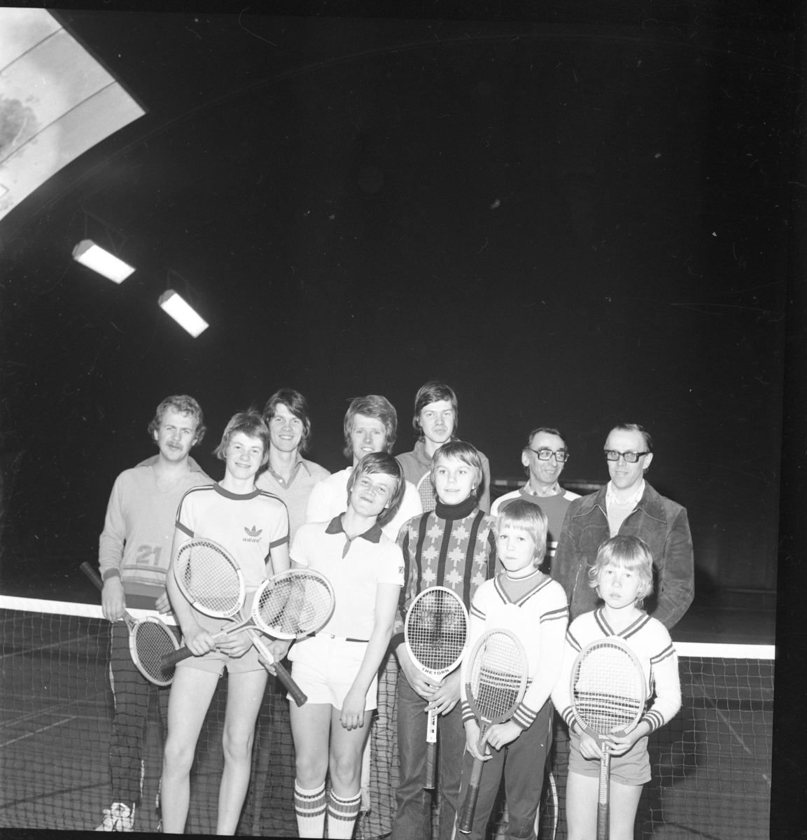 Elva vuxna och ungdomar med tennisrack.