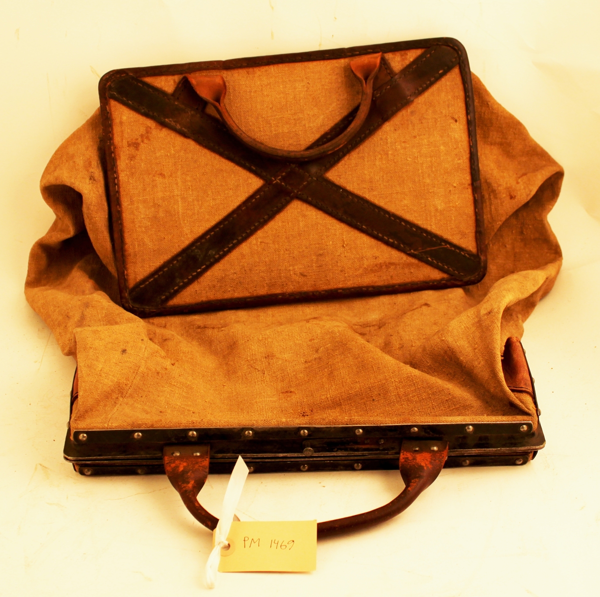 Tömningsväska av säckväv med järnram till mekanisk brevlåda. Väskan är fästad vid den rektangulära järnramen. Järnramen är försedd med gångjärn, så den kunde vikas ihop och förslutas med en låshake. Ett läderhandtag är fäst vid ramen. I väskans botten en hård pappskiva. Pappskivans kanter är förstärkta med påsydda skinnband, samt på botten ett kors av skinnband. Under korsets
skinnband är ett läderhandtag fästat.