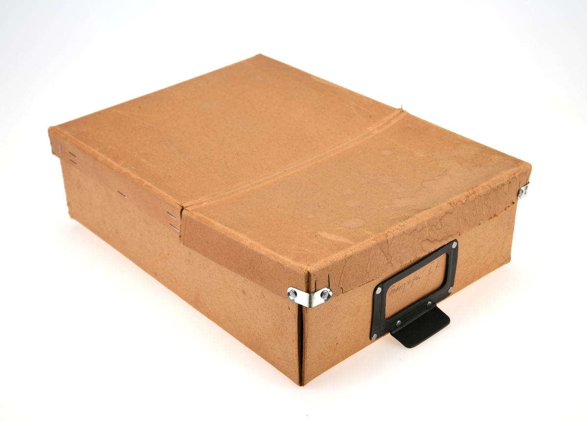 En arkivboks brukt til oppbevaring av fotografier. Boksen har et lokk som er hengslet på midten. Den ene kortsiden kan også brettes ned. På fronten av boksen er det en holder til en etikett med et lite håndtak på.