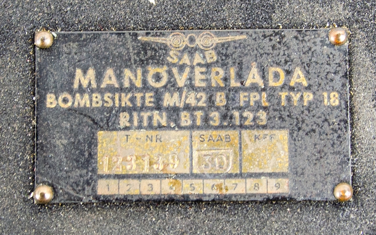 Manöverlåda för bombsikte M/42b till flygplan B18. Tillverkad av metall, svart färg. Panel sliten. Tillverkad av SAAB, ritningsnummer: BT3.123.