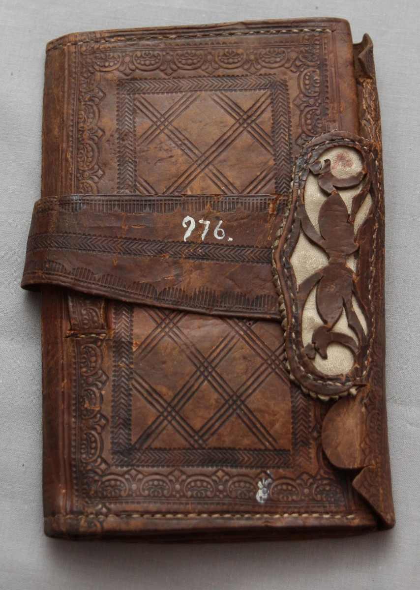 Plånbok i läder med pressad dekor. Med två sedelfack och ett mindre fack.
