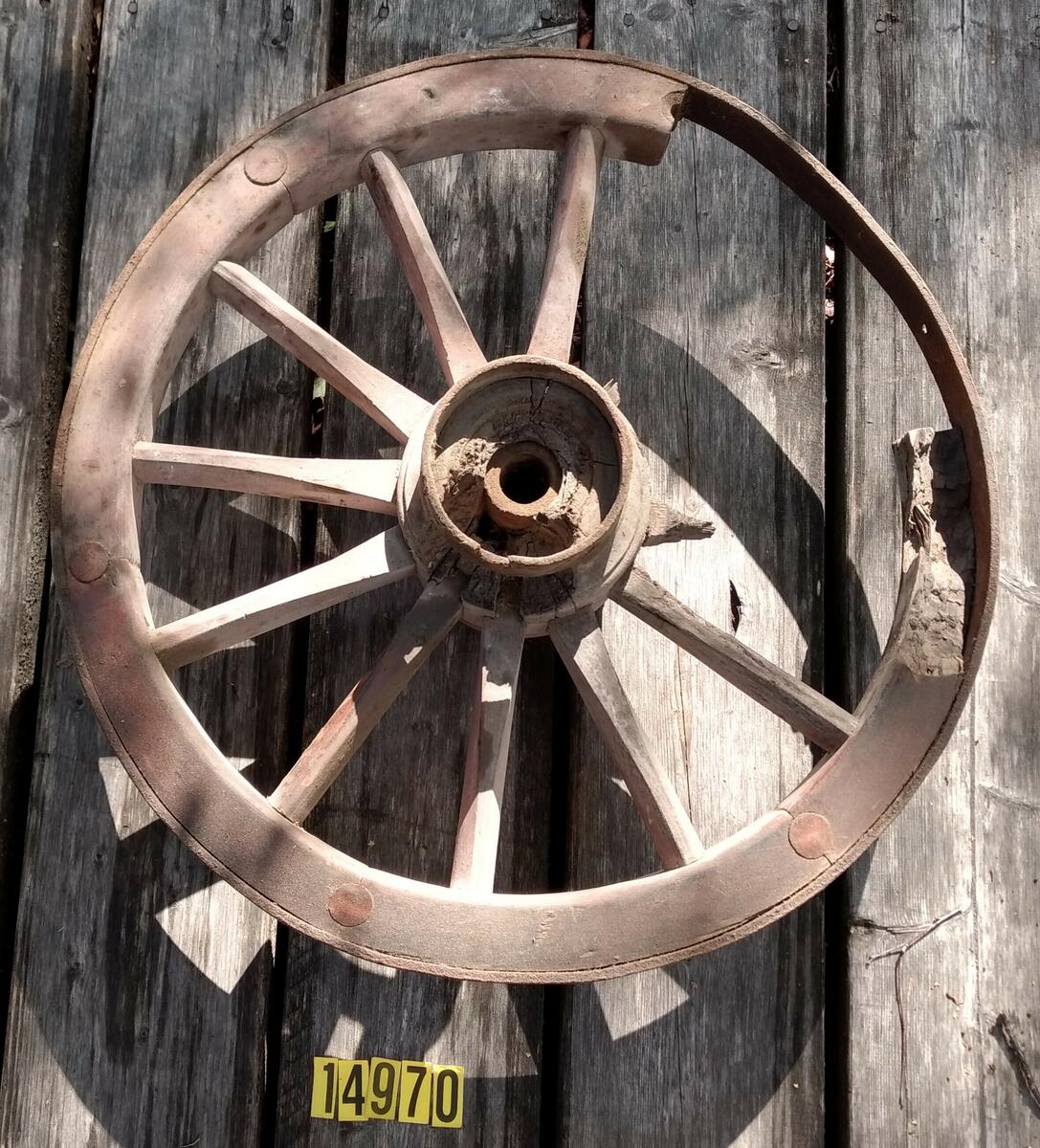 Rödmålat hjul med tolv ekrar, två tre saknas. Hel järnskoning runt nav och hjul. Hjulet / Löte är delat i sex delar med två ekrar. 1/6 av lötet saknas helt och 1/6 är skadad. Kan ev. vara MFF4141? De har bredd 63 cm. Plac: L1AA2.