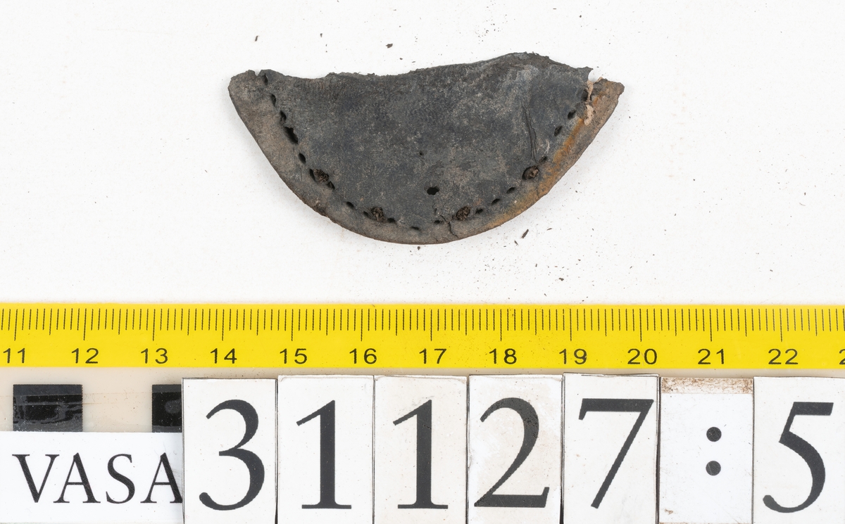 Delar och fragment från sko; tre sulor, en holtrand, en klacklapp, en klacklapp eller ett inlägg samt ett 40-tal delar och mindre fragment från skoöverdel och skobotten.
Sula fyndnummer 31127 har kvarsittande tråd. På sulans ovansida finns intryck av bindtråden.  Sula fyndnummer 31127:1 har kvarsittande träpligg och tråd. I tåpartiet finns en laglapp. Sulans hälparti är avskuret, eventuellt avbrutet.  Sula fyndnummer 31127:2 har ett fragmentariskt hälparti. På sulans ovansida finns intryck av bindtråd. Holtrand fyndnummer 31127:3 har kvarsittande tråd. På klacklapp fyndnummer 31127:4 finns hål efter träpligg. På klacklapp, eventuellt inlägg, fyndnummer 31127:5 finns kvarsittande tråd.