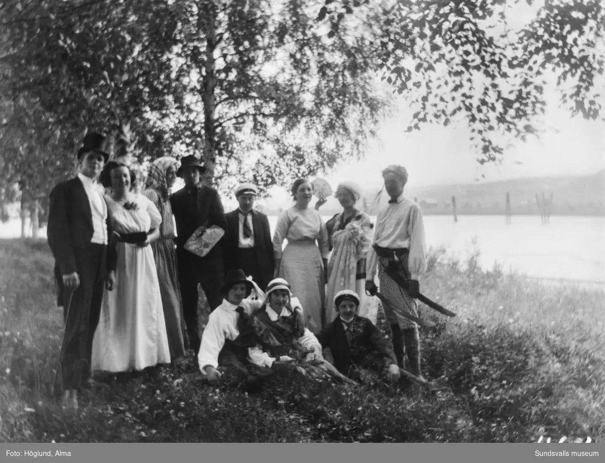 Gruppbild invid Stödesjön med elva ungdomar i gröngräset. Någon form av festlig utflykt, ungdomarna är utklädda till olika karaktärer.