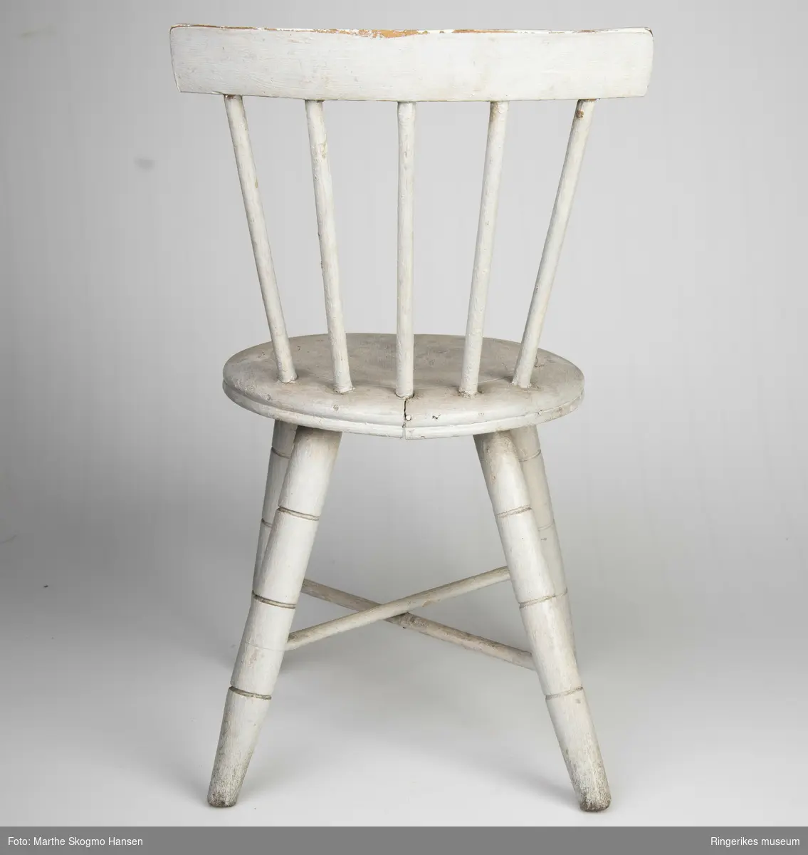 Stolen er veldig pent laget, den ser akkurat ut som en stol for voksne, bortsett fra størrelsen. Det er en typisk pinnestol, med rundt sete. Beina har tre dekorative furer hver, 8,5 cm, 16 cm og 22 cm opp fra gulvet. Det er to sarger i kryss. Ryggen består av 5 pinner på 20.5 cm og et smalt ryggbrett på toppen, 4,5 cm bredt. Stolen er malt lys grå, men fargen er slitt vekk noen steder, av og til ned til den hvite grunningen, andre ganger er det slitt ned til treverket.Det er en sprekk på tvers av setet, men ellers er stolen i god stand.