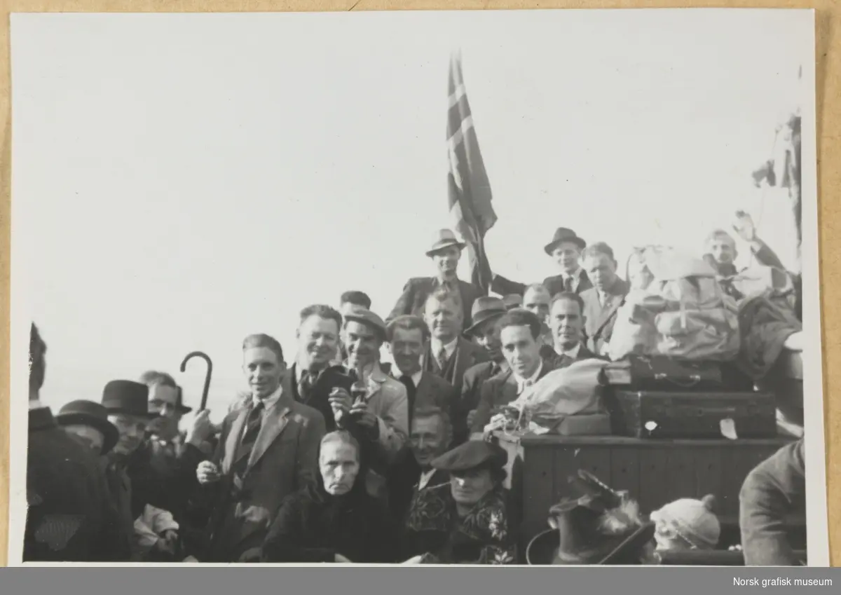 Gruppebilde. Mange mennesker sittende og stående tett i tett, antatt ombord på en rutebåt. Kofferter og ryggsekker står stablet mellom menneskene. Fotografert i forbindelse med Vestlandsk Trykkerstevne i Bergen, 1946.