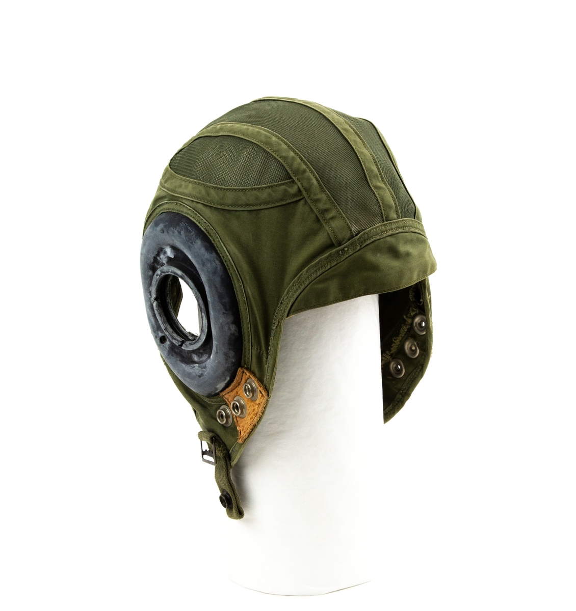 Flyghuva utförd i grönt tyg samt grönt nylonnät där ett gummiskydd för öronen saknas. Hakband saknas. Blå textiletikett fastsydd på insidan med gul text "H-4 Size 6 5/8".