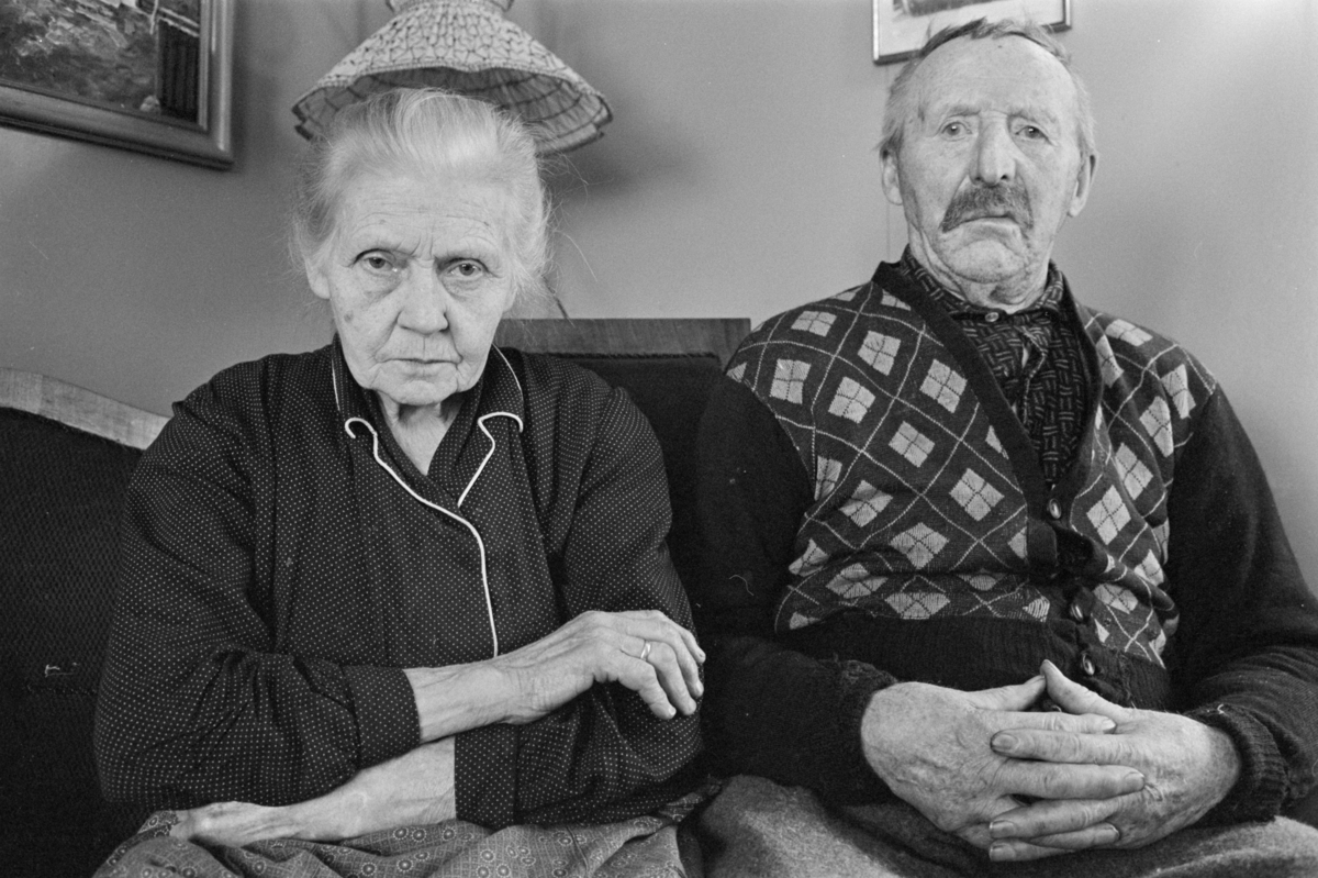 En kvinne og en mann sitter i en sofa.