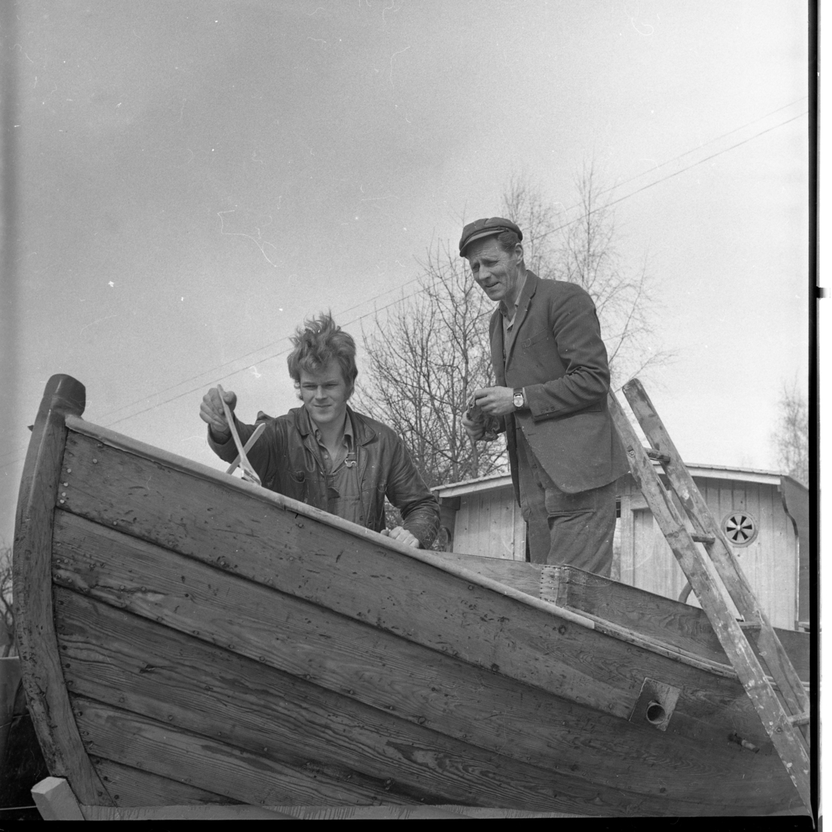 Två män står i en träbåt.