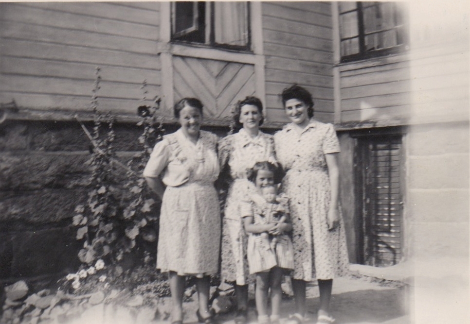 Tre kvinnor och ett barn står utanför bostadshuset Labacka 1:2 "Lund" cirka 1930. Till vänster står "Lisa" Johansson (1898-1997). Övriga är sommargäster.