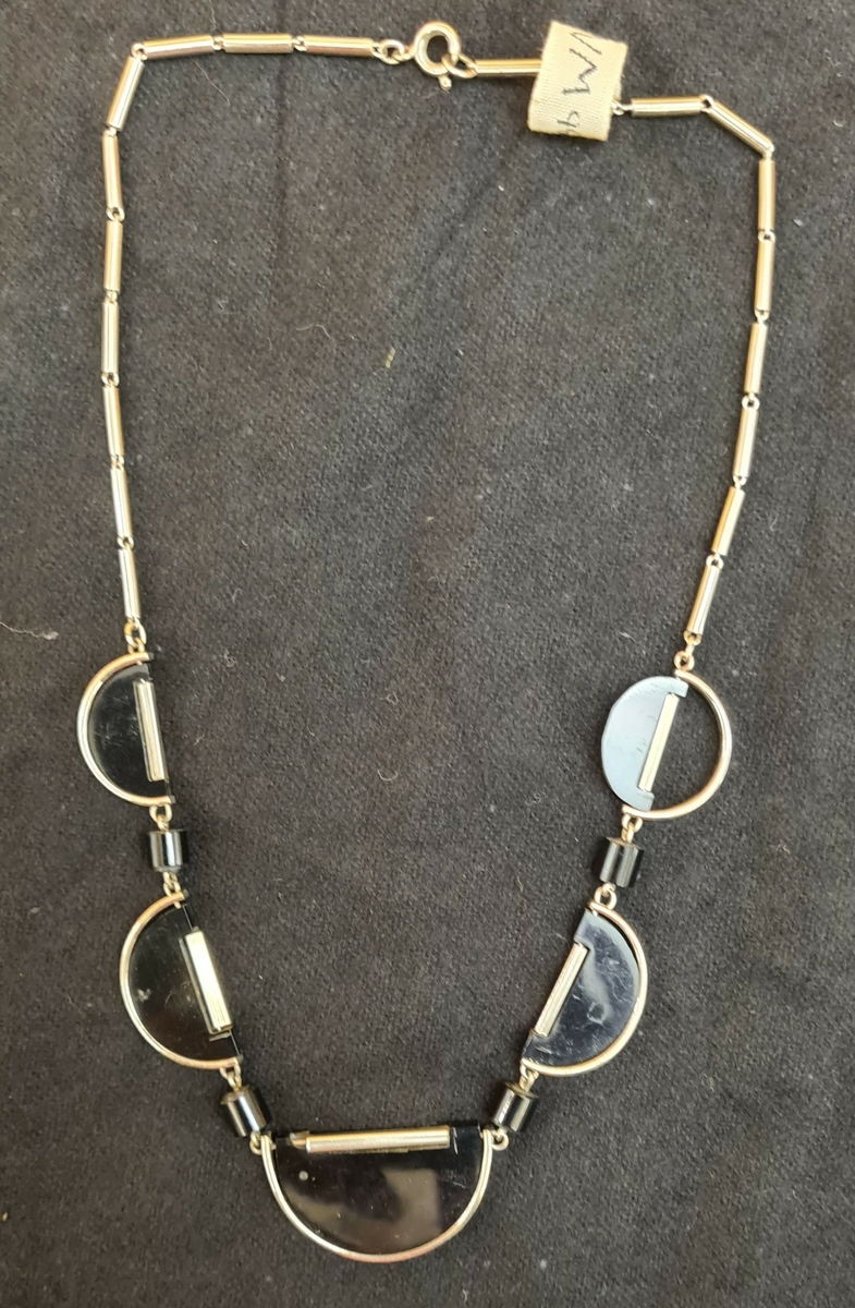 Halsband: Svarta och silverfärgade cirklar. Plast.

Tillhör klänningen VM09202:a.