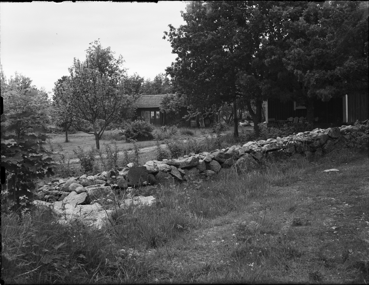 Litet hus med trädgård och en stenmur i förgrunden, Uppland