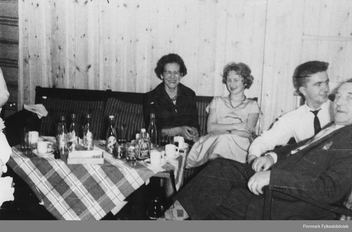 Portrettfotografi av en gruppe på to kvinner og to menn som var med på å feire åpningen av R.v.93 Autsi-Suolovobme. Feiringen foregikk på Alta hotell. De to kvinnene er ukjente. Mennene er Kåre Rønning og Odin Holsmo.