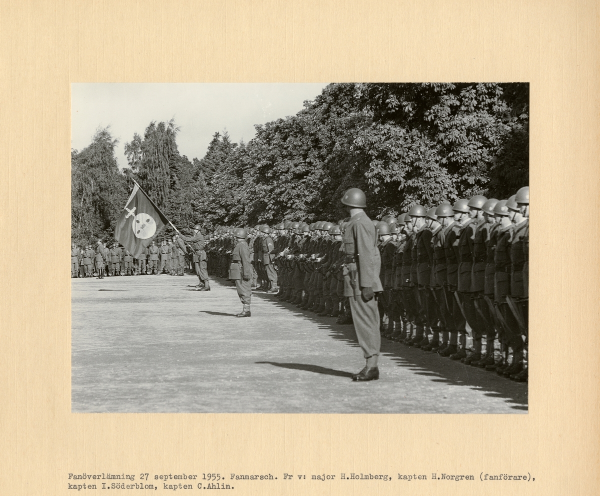 Text i fotoalbum: "Fanöverlämning 27 september 1955. Fanmarsch. Fr v: major H. Holmberg, kapten H. Norgren (fanförare), kapten I. Söderblom, kapten C. Ahlin".