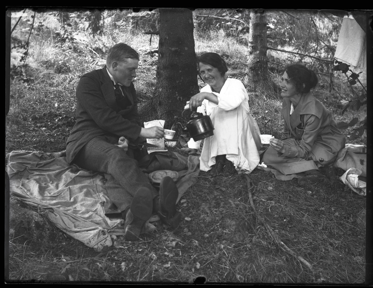 Tre personer i skogen dricker kaffe.
