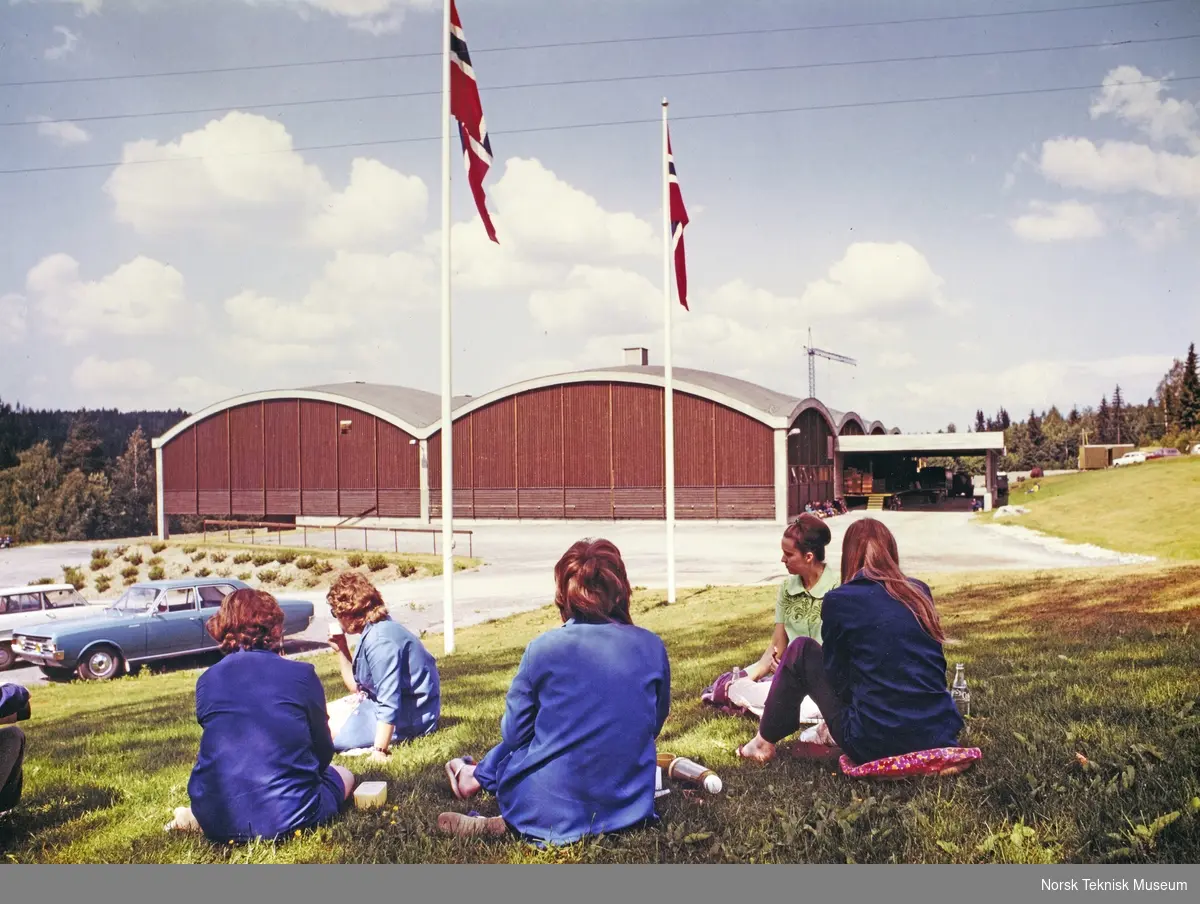 Arbeidere ved ELKO-fabrikken på Sporpind i Åmot, Modum, har matpause i sola utenfor fabrikken ca. 1970-71.