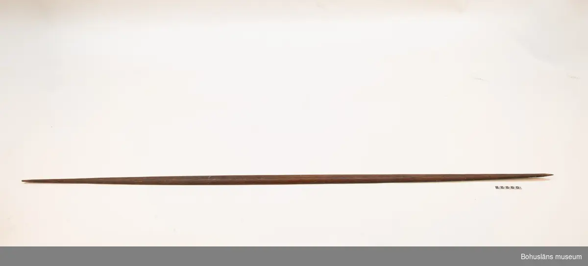 Ur handskrivna katalogen 1957-1958:
Pilbåge, Kongo, Afrika
L. 206,5 cm; på ena sidan svart, på andra rödbrun m. 2 svarta linjer i mitten. Strängen trasig, f. övr. hel.
Sträng saknas vid inventering 20220607.

Lappkatalog: 9