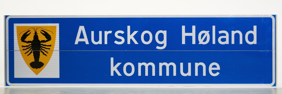 Et våpenskjold for Aurskog-Høalnd før regionalreformen med en kreps som symboliserte krepsefiskeriet i kommunen.