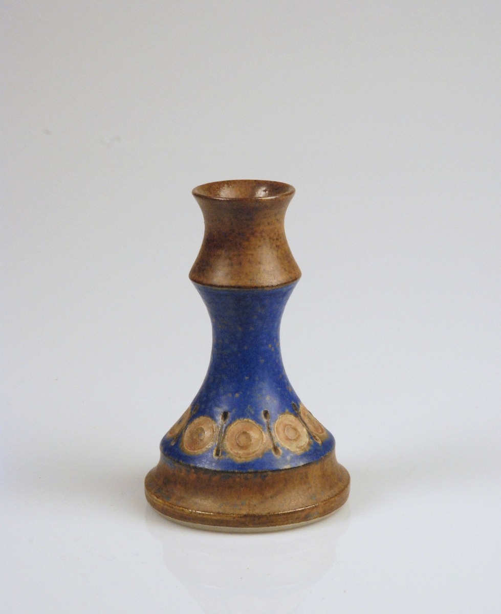 Ljusstake med blå och brun glasyr. Dekor i form av rundlar,

Undertill märkt: 
Stämpel: Alingsås Keramik 331 Handgjort stengods
Ristat: U. Winblad
