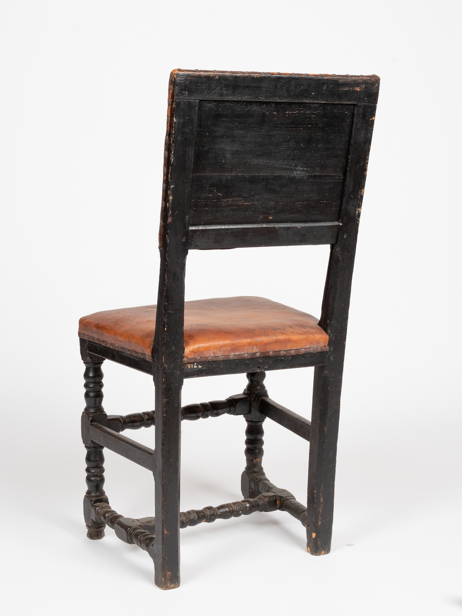 A-B: 2 stk. stoler i barokk stil med skinntrekk. Dreide ledd på de to fremste bena, for- og bakben sammenbundet med sidesprosser, rygg og sete stoppet og skinntrukket, malt. Rett sarg, rygg og sete, rektangulært ryggfelt.
