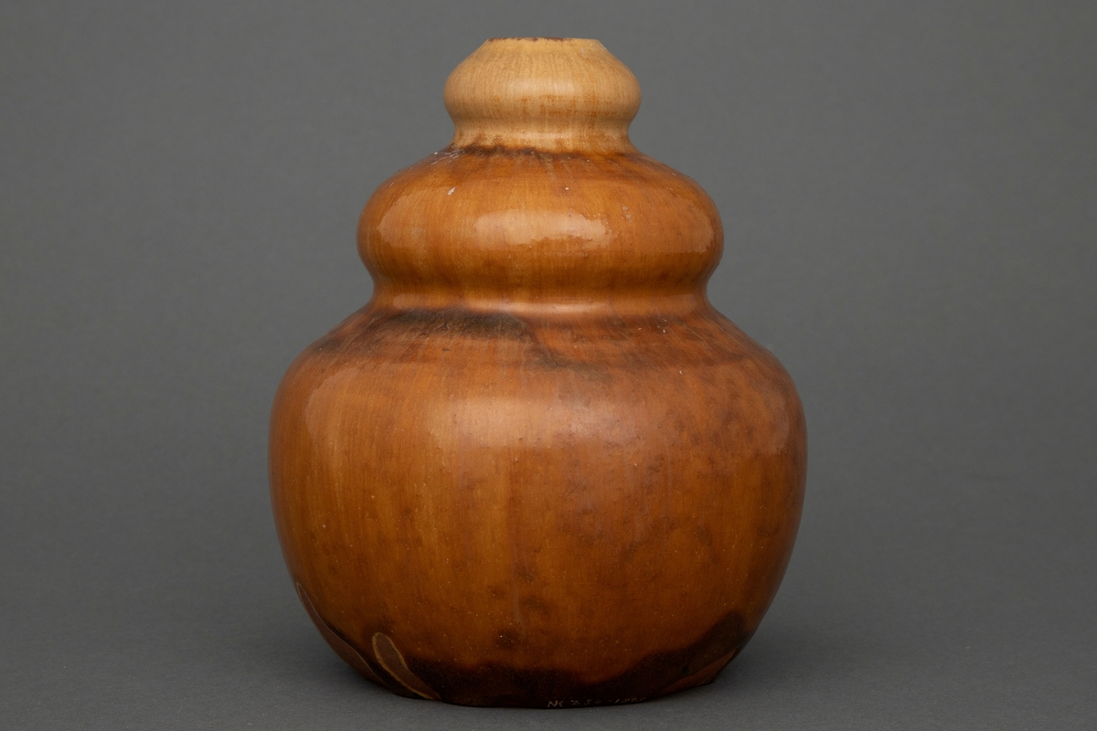 Vase i dreid steingods med kalebassform og gulbrun glasur med flamme-effekter.
