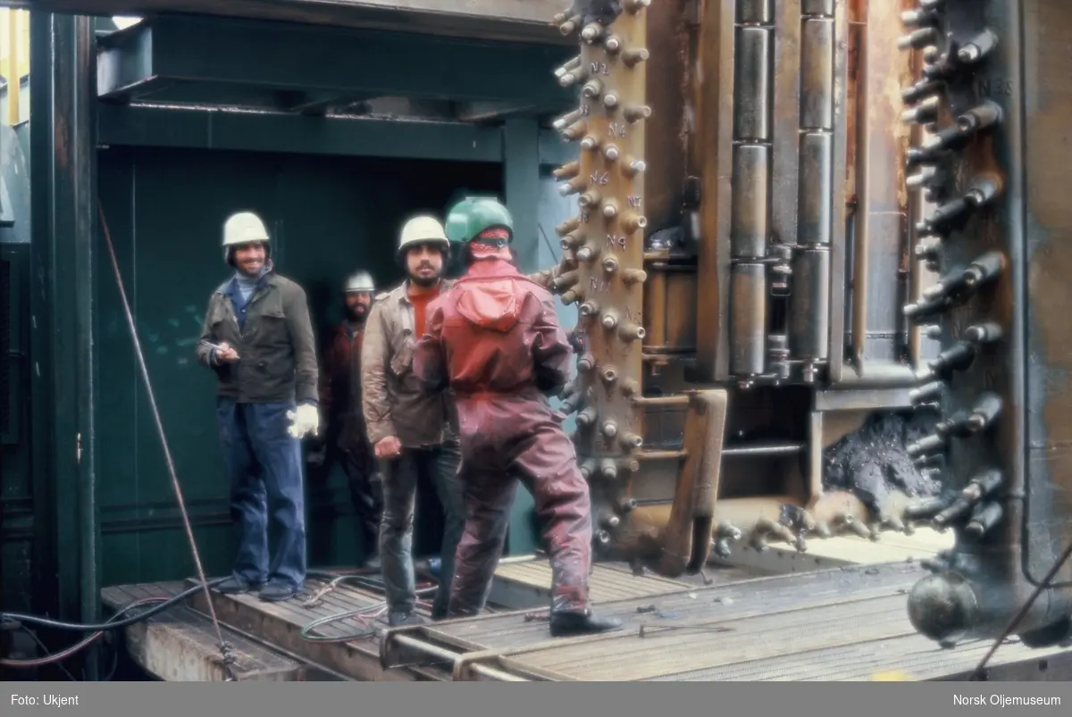 En glad gjeng med arbeidere står bak en mann som sveiser på en installasjon. De to siste bildene er nærbilder av det de arbeider med.