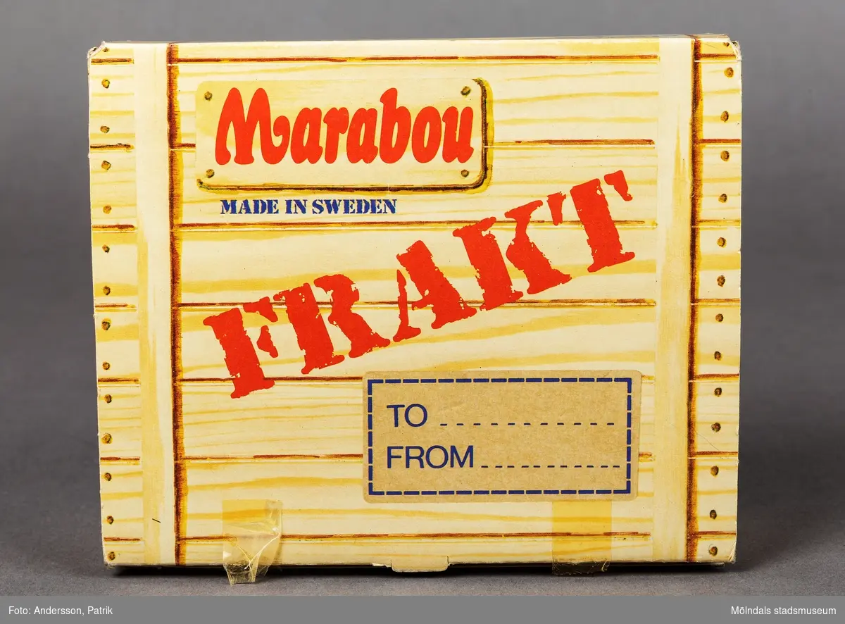 En ask i kartong som tidigare innehållit olika sorters choklad och godis av varumärket Marabou. Asken köptes vid flyg och charterresor på 1980-1990 talet. Asken är utformad så att den föreställer en fraktlåda i trä. På askens lock finns en etikett med plats att skriva mottagare och avsändare. På asken står det Marabou med stora röda bokstäver och Frakt med ännu större bokstäver. Asken innhöll vid köp, många olika sorters godis som Plopp, Dajm, Japp, Käck, Rollo, Non Stop med mera.
På askens sidor står namnen på olika  stora städer som New York, Las Palamas, Oslo med flera.