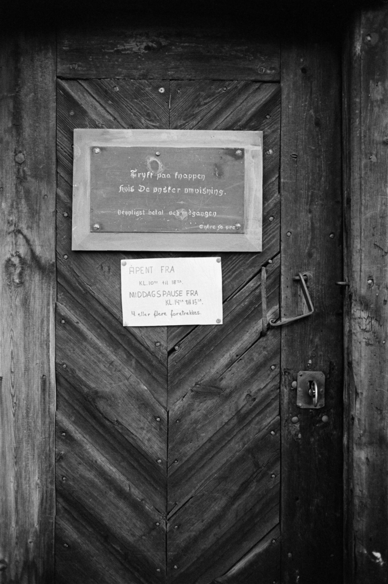 Et skilt med "Trykk paa knappen hvis De ønsker omvisning" på døra til Røros kirke. 