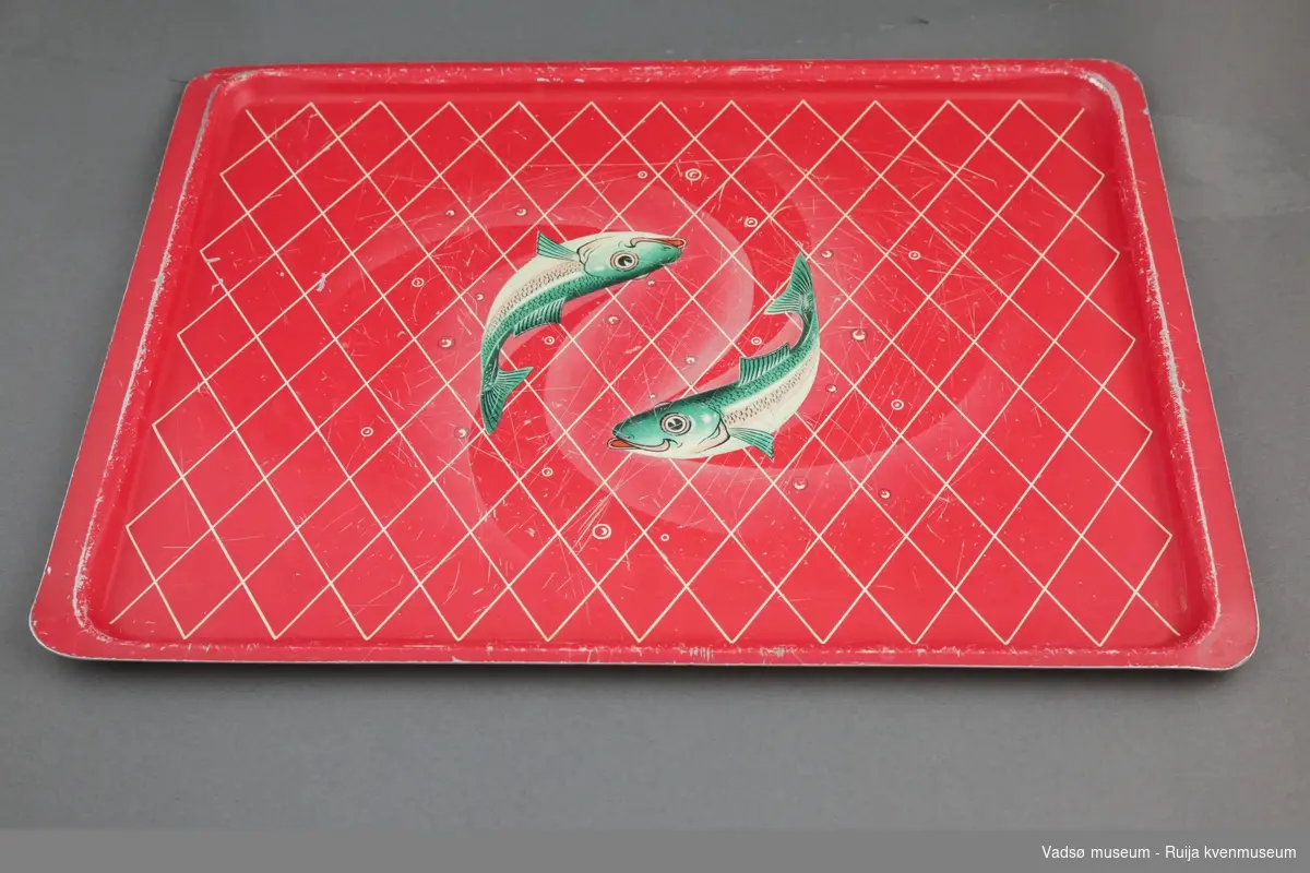Rødt serveringsbrett med hvitt rutemønster. Motivet i midten viser to smilende sardiner.